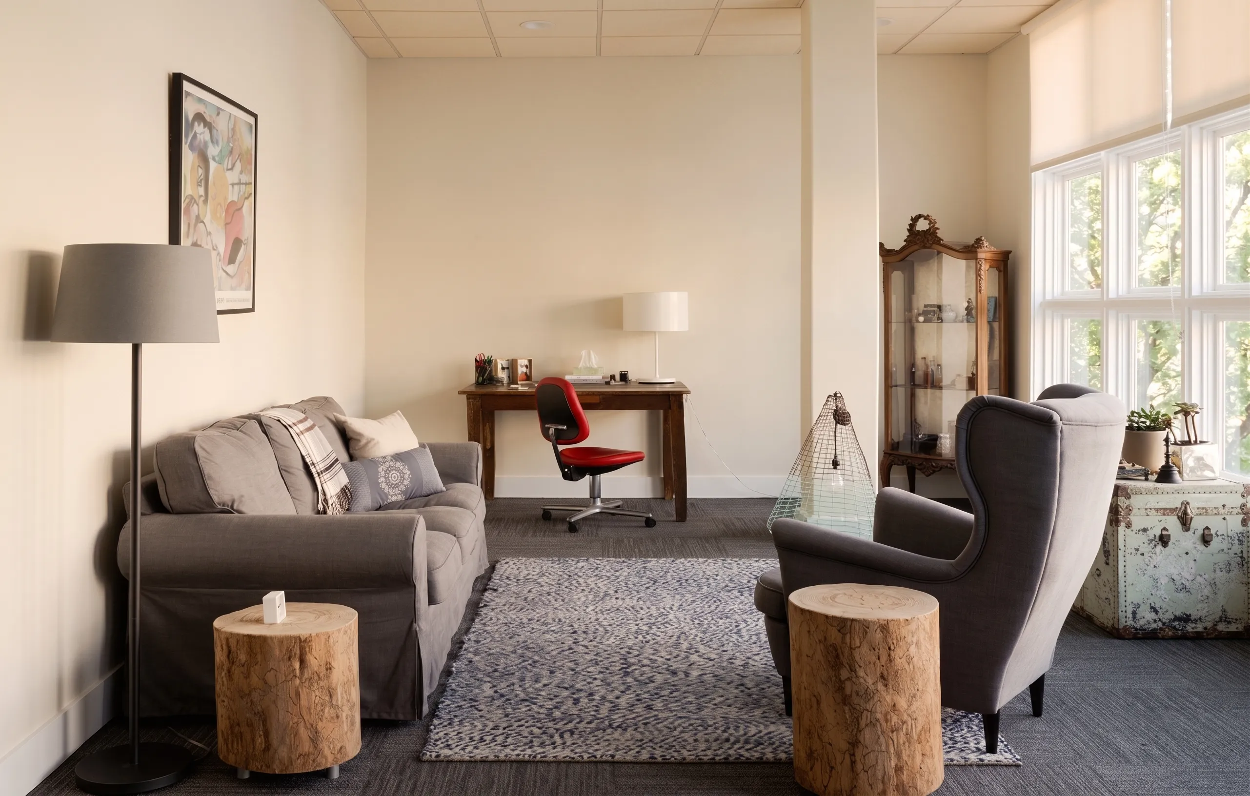 A quiet individual-therapy room at The Lovett Center, with a soft gray sofa, warm wood side tables, and natural light.