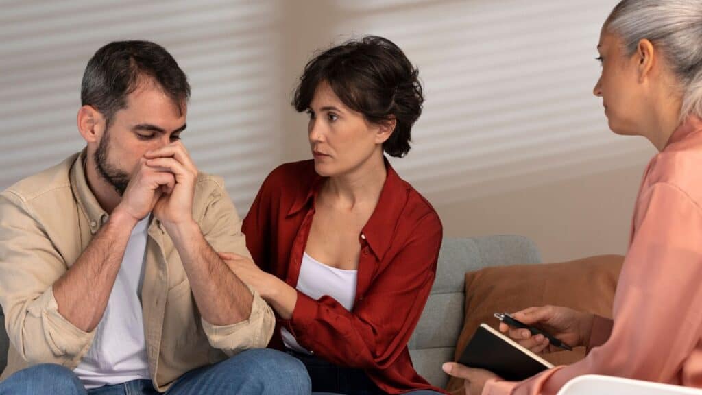 A man receives support from his wife and therapist during family therapy in Houston.