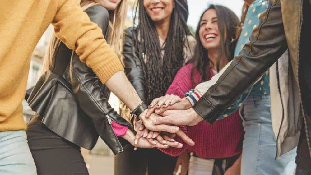 several people of different backgrounds join hands, symbolizing togetherness and community spirit