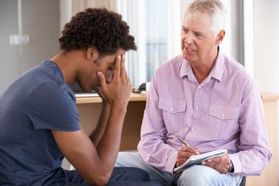 a therapist speaking to a man in a mat program