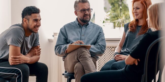 group of individuals in therapy discussing the topic of PHP versus IOP programs